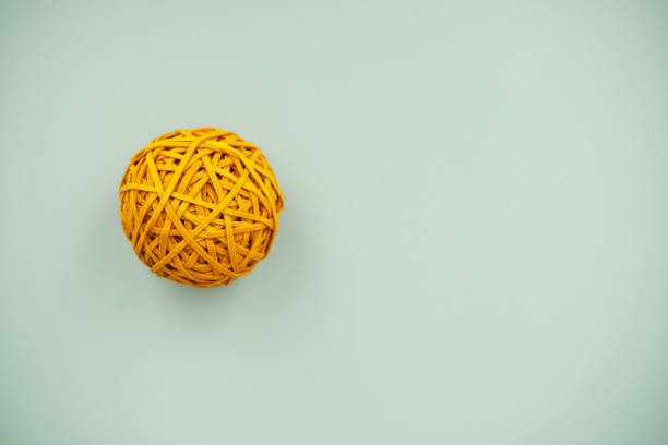 yellow rubber band ball on mint green background with copy space - rubber band rubber intertwined flexibility imagens e fotografias de stock