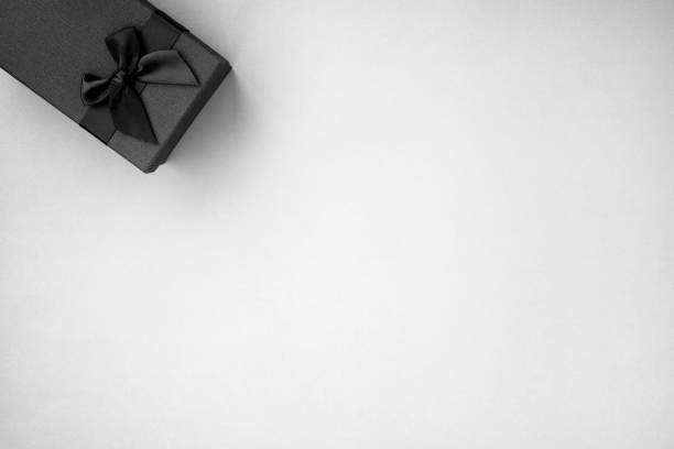 Gift black box with black ribbon on white background. Top view, copy space