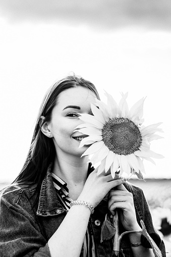 Brunette woman in denim jacket on the field with sunflowers. Close plan. Summer content. Beauty content. Black and white photography.