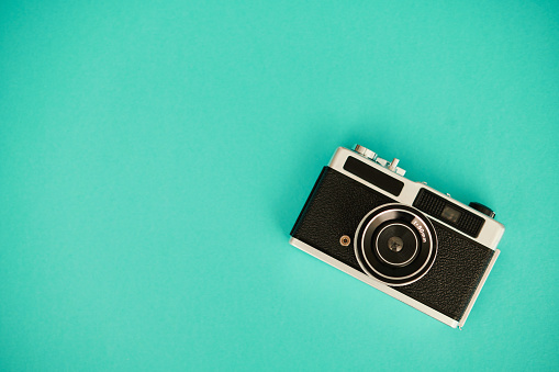 Vintage film camera on teal background with copy space