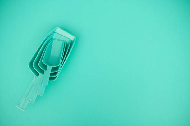 Teal measuring spoons on a teal background with copy space