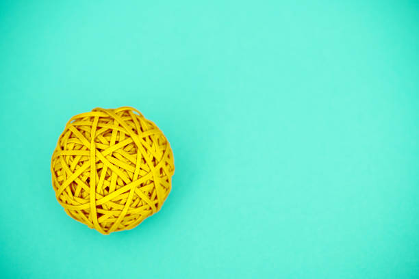 palla elastica gialla su sfondo verde con spazio di copia - flexibility rubber rubber band tangled foto e immagini stock
