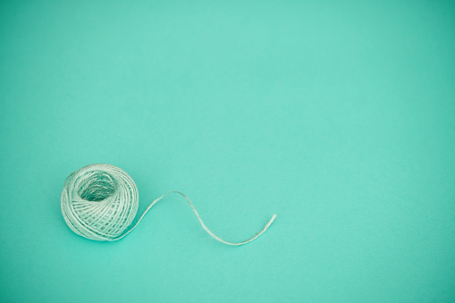 Teal ball of string on a teal background with space for copy