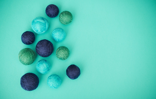 Collection of small balls of string on teal background