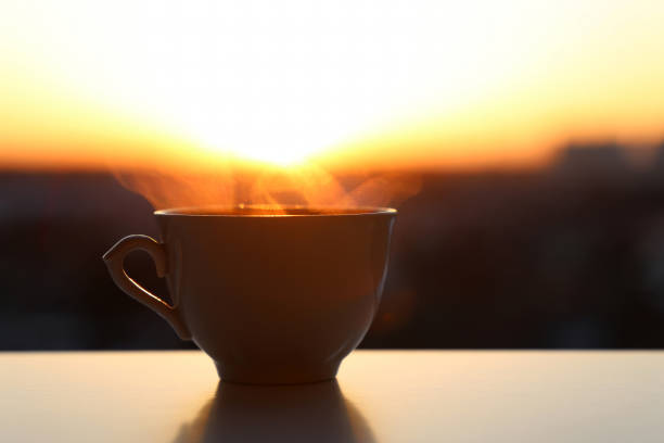 istock Hot coffee cup with smoke on sunrise background 1363654448