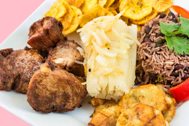 Studio shot. The creole meal includes deep-fried pork meat, congri rice, boiled cassava and banana chips.