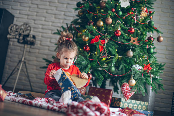 istock Cute little toddler opening present near Christmas tree 1363655249