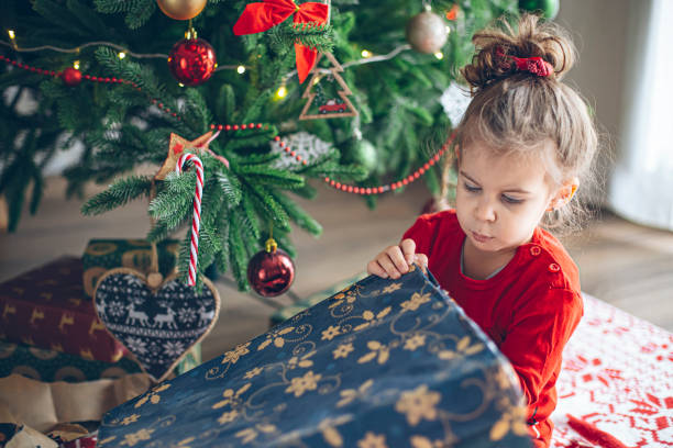 istock Cute little toddler opening present near Christmas tree 1363656352
