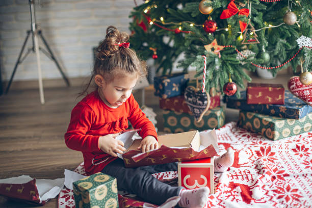 istock Cute little toddler opening present near Christmas tree 1363656525