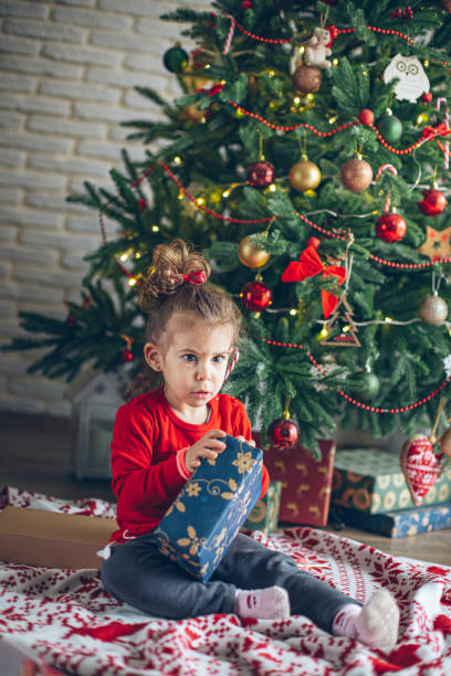 istock Cute little toddler opening present near Christmas tree 1363656569