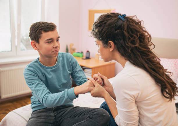 Mother having serious talk with boy at home stock photo