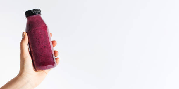 istock A woman's hand holds a glass with berry smoothies on a white background. Banner 1363661576