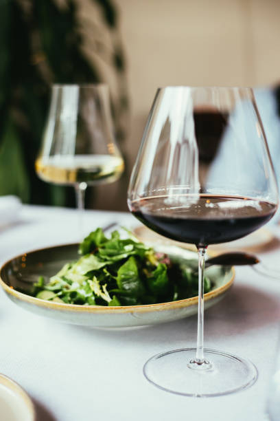 bicchieri di vino rosso e bianco e insalata verde sul tavolo - divided plate foto e immagini stock