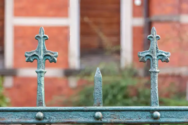 Stylish ornamental metal spikes on the top bar of a fence or railing outside a brick building in close up