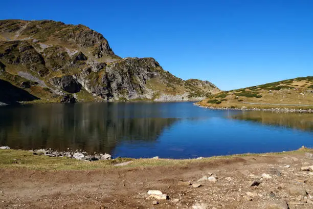 Photo of mountain lake on a sunny day, mountains are reflected in the water