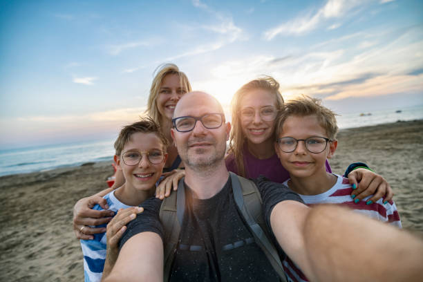 Parents and kids taking selfie on a beach in the evening