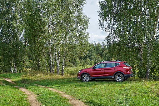 Tver region, Russia - August 14, 2021: Dark red car Nissan Qashqai is parked in a beautiful place near country road. Auto travel concept