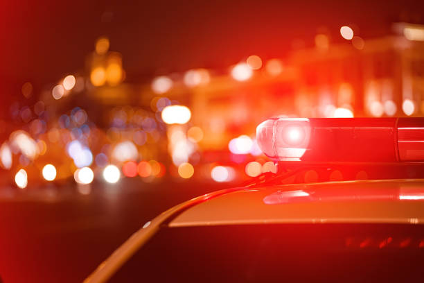 Police car red color emergency light (siren) at the night city lights background. stock photo