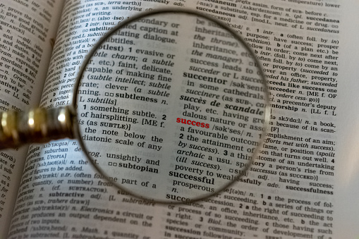 A conceptual image. Magnifying glass frames the word success in a dictionary.