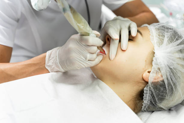 istock Permanent make-up artist and her client during lip blushing procedure 1363681052