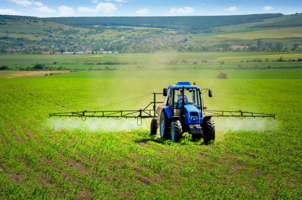 Farming tractor plowing and spraying on field stock photo