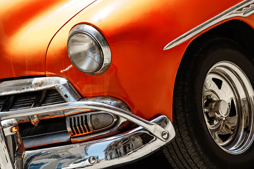 Close up of a shiny vintage orange car parked on street