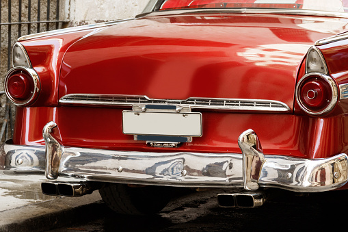 Rear view of a shiny vintage red car parked on street.