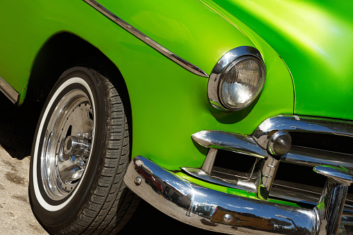 Close up of a shiny vintage green car parked on street.