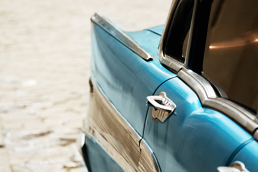 Close-up of a rear side of a shiny old blue car.