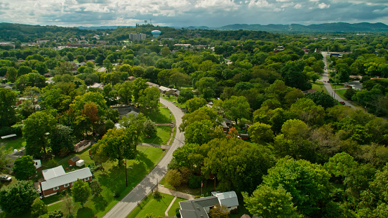 Aerial shot of a residential neighborhood in the southern suburbs of Nashville, Tennessee, with a view across the thickly wooded rolling landscape towards the foothills of the Appalachian Mountains. \n\nAuthorization was obtained from the FAA for this operation in restricted airspace.