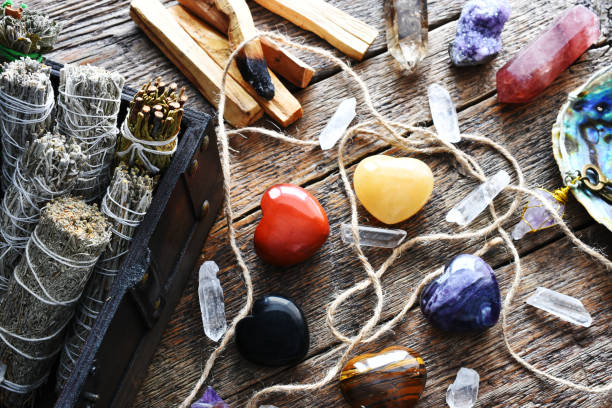 Heart Shaped Healing Crystals A top view image of several heart shaped healing crystals with white sage smudge sticks and clear quartz crystals on a dark wooden table top. calcite stock pictures, royalty-free photos & images