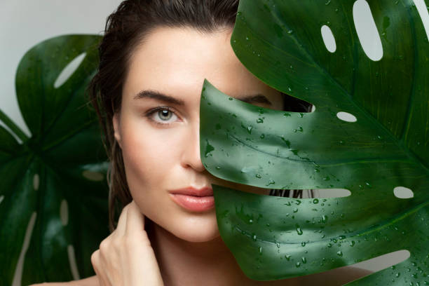 Beautiful woman with a wet tropical leaf stock photo