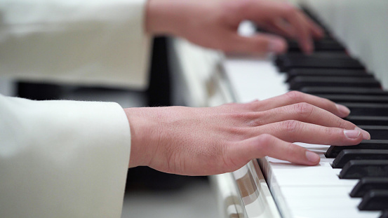 Close up of woman's hand playing the piano.