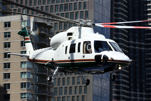 A Sikorsky S-76 helicopter departing from New York's East 34th Street Heliport. Manhattan skyscrapers in the background.  New York, New York, USA.  June 2017.
