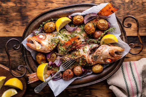 Delicious whole baked redfish with chimichurri sauce, baby potatoes, red onion, lemon and thyme.