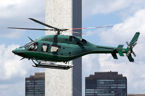 A Bell 429 GlobalRanger helicopter arriving from New York's East 34th Street Heliport. Manhattan skyscrapers and the UN Building in the background.  New York, New York, USA.  June 2017.