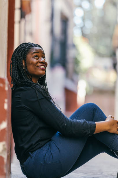 istock African woman looking up while sitting on the street 1363693208