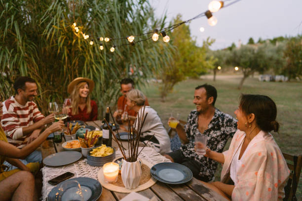 friends having a summer dinner party - dineren stockfoto's en -beelden