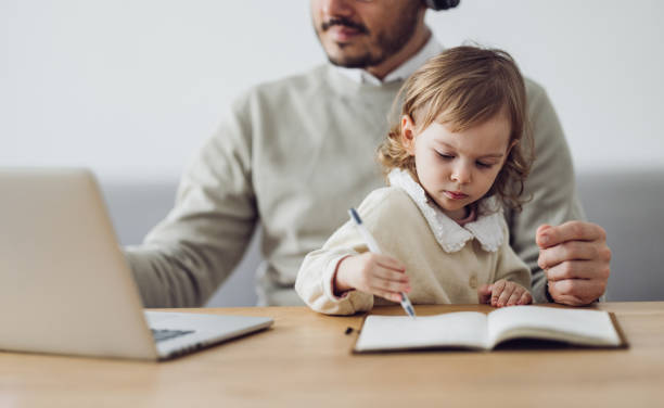 istock Home Office: Man Having a Video Call and Holding a Kid 1363697797
