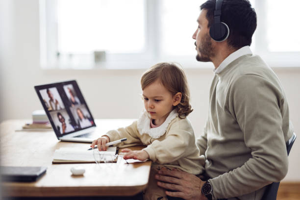 istock Home Office: Man Having a Video Call and Holding a Kid 1363697800