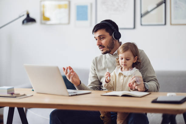 istock Home Office: Man Having a Video Call and Holding a Kid 1363697803