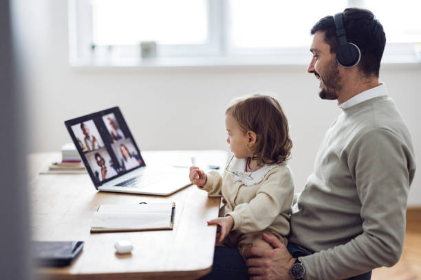 istock Home Office: Man Having a Video Call and Holding a Kid 1363697804