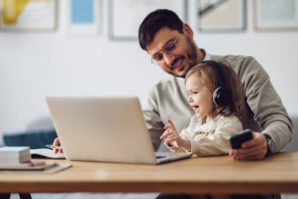 istock Home Office: Man Having a Video Call and Holding a Kid 1363697811