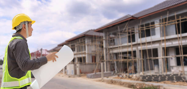 istock young professional engineer in protective helmet and blueprints paper at the house building construction site 1363698619