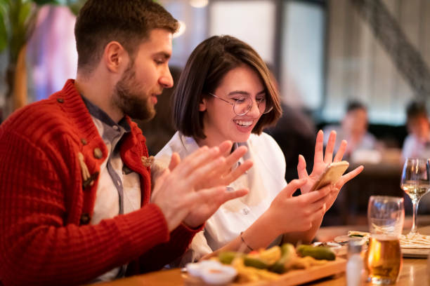 istock Happy young couple using a smartphone together at the restaurant 1363698656