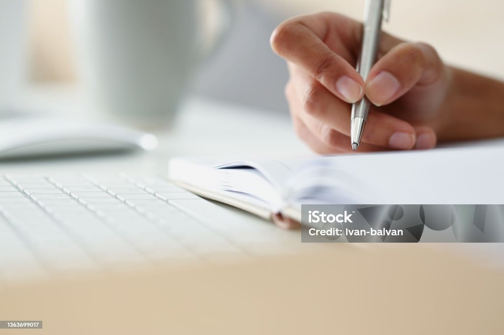 Persons hand writing down ideas in diary, notes for future, planning day in advance Close-up of persons hand writing down ideas in diary, notes for future, planning day in advance. Write with silver pen. Journal, creativity, writer concept Dissertation Stock Photo