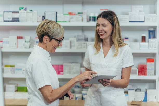 istock Senior female pharmacist talking with a young colleague and using a digital tablet 1363699276