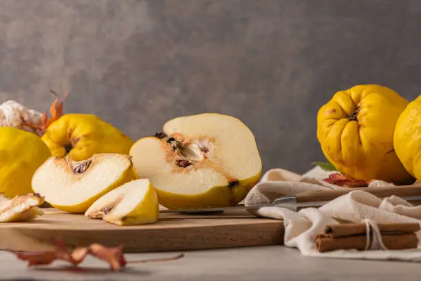 Ripe whole and sliced quinces. Fresh fruit for preparing recipes with cinnamon and lemon. An essential ingredient for a healthy diet