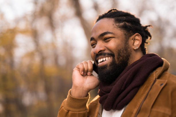 istock Happy African American man talking on phone while walking in the park. 1363710036