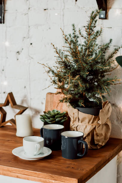 istock A small Christmas tree in a pot on a kitchen set. Mugs and a cup and saucer on the table top. 1363722434
